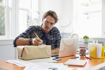 Man At Home Addressing Package For Mailing