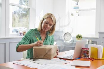 Woman At Home Addressing Package For Mailing