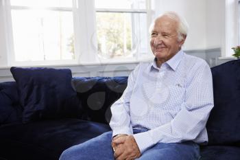 Smiling Senior Man Sitting On Sofa At Home