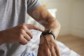 Man Wearing Pajamas Checking Smart Watch In Bedroom