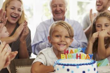 Boy Blows Out Birthday Cake Candles At Family Party