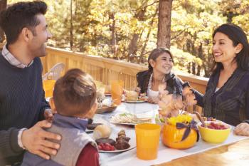 Happy family eating at table on a deck in a forest