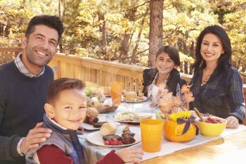 Happy family at a table on a deck in a forest look to camera