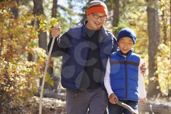 Asian father and son hiking in a forest, embracing