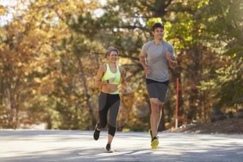 Caucasian woman and man jogging on a country road