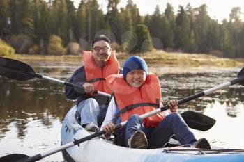 Father and son kayaking on a rural lake, front view