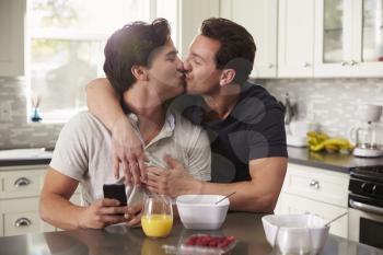 Male gay couple in their 20s kissing in their kitchen