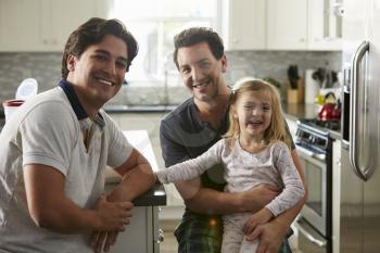Male gay couple sitting with their daughter in the kitchen