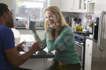 Mixed race couple talking in the kitchen, woman laughing