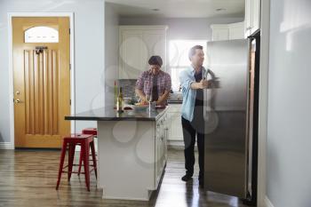 Male couple in the kitchen preparing a meal, opening fridge