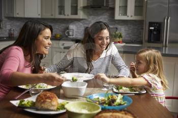 Female gay couple and daughter having dinner in their kitchen