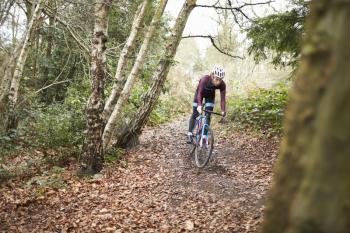 Cross-country cyclist riding on a forest trail, front view