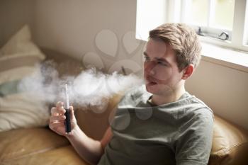Young Man Using Vapourizer As Smoking Alternative