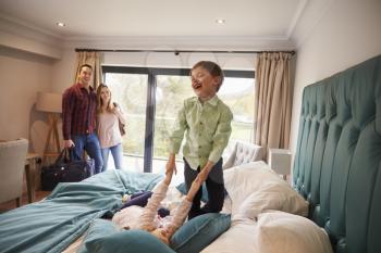 Family On Vacation With Children Playing On Hotel Bed