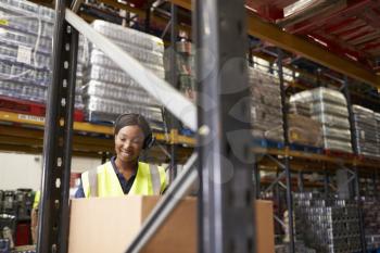 Woman using barcode reader in warehouse, head and shoulders