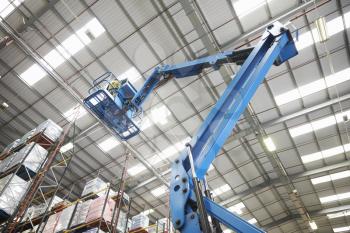 Moving stock in a warehouse with a cherry picker, low angle