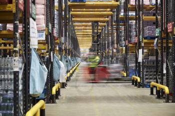 Forklift driving across an aisle in a warehouse, motion blur