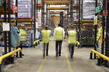Staff in reflective vests walking from camera in a warehouse