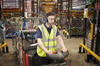 Man driving a tow tractor through a distribution warehouse