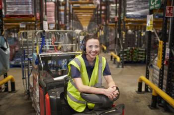 Young woman leaning on tow tractor in distribution warehouse