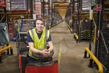 Young man leaning on tow tractor in distribution warehouse