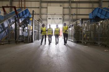 Four colleagues walking into a warehouse, wide view