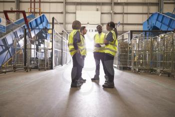 Four staff in discussion in a warehouse, low angle view