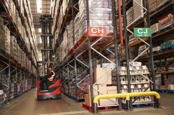Man using aisle truck in a distribution warehouse, side view