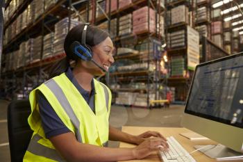 Woman with headset working in on-site office of a warehouse