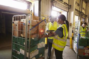 Warehouse manager oversees a woman preparing a delivery
