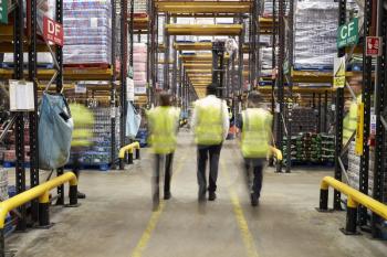 ESSEX, ENGLAND- MAR 13 2016: Staff in reflective vests walking away from camera in a supermarket distribution warehouse