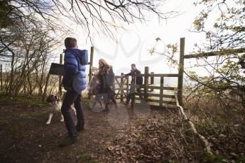 Family walking their dog pass through a gate in countryside