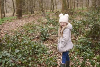 Young girl standing alone in forest undergrowth