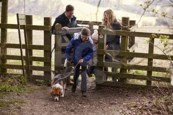 Family with a dog passing through a gate in the countryside