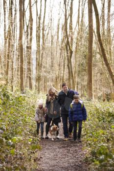 Family with pet dog walking in a wood, vertical