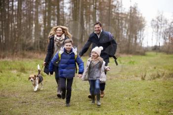 Family walking dog together in the countryside, front view
