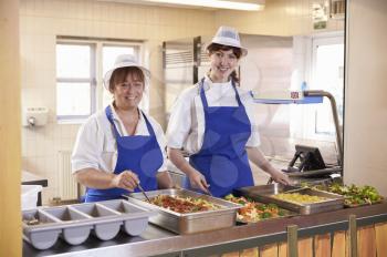 Two women waiting to serve lunch in a school cafeteria