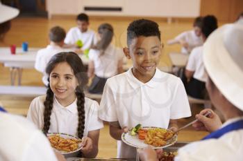 Over shoulder view of kids being served in school cafeteria