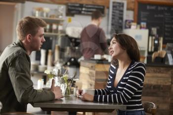 Adult couple talking at a table in a coffee shop, side view
