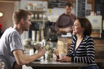 Adult couple talking at a table in a coffee shop, side view