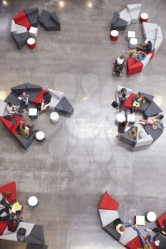 Students groups sit in a modern university atrium, vertical