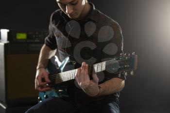 Close Up Of Man Playing Electric Guitar In Studio