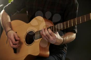 Close Up Of Man Playing Acoustic Guitar In Studio