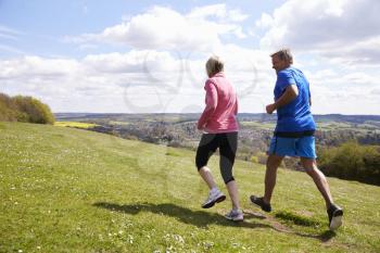Rear View Of Mature Couple Jogging In Countryside