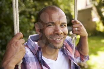 Head And Shoulders Shot Of Mid Adult Man Sitting On Swing
