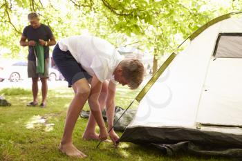 Father And Teenage Son Putting Up Tent On Camping Trip