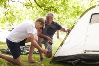 Father And Teenage Son Putting Up Tent On Camping Trip