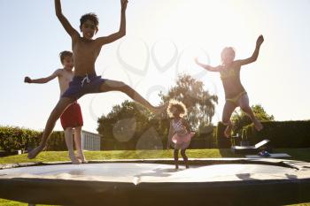 Group Of Children Having Fun Jumping On Outdoor Trampoline