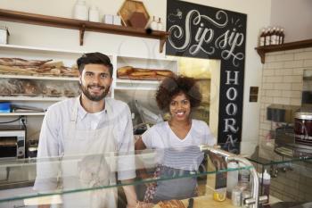 Mixed race couple behind counter at sandwich bar, close up