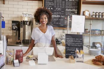 Smiling waitress behind counter at a coffee shop, close up